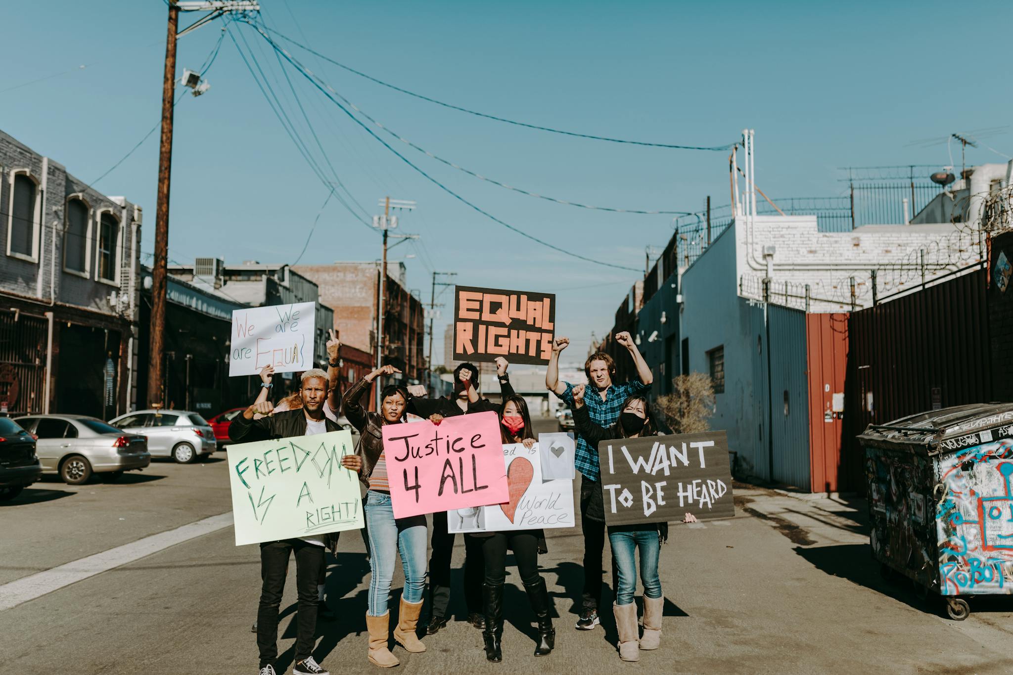 Diverse group of people holding signs advocating for equal rights during a peaceful protest outdoors.
