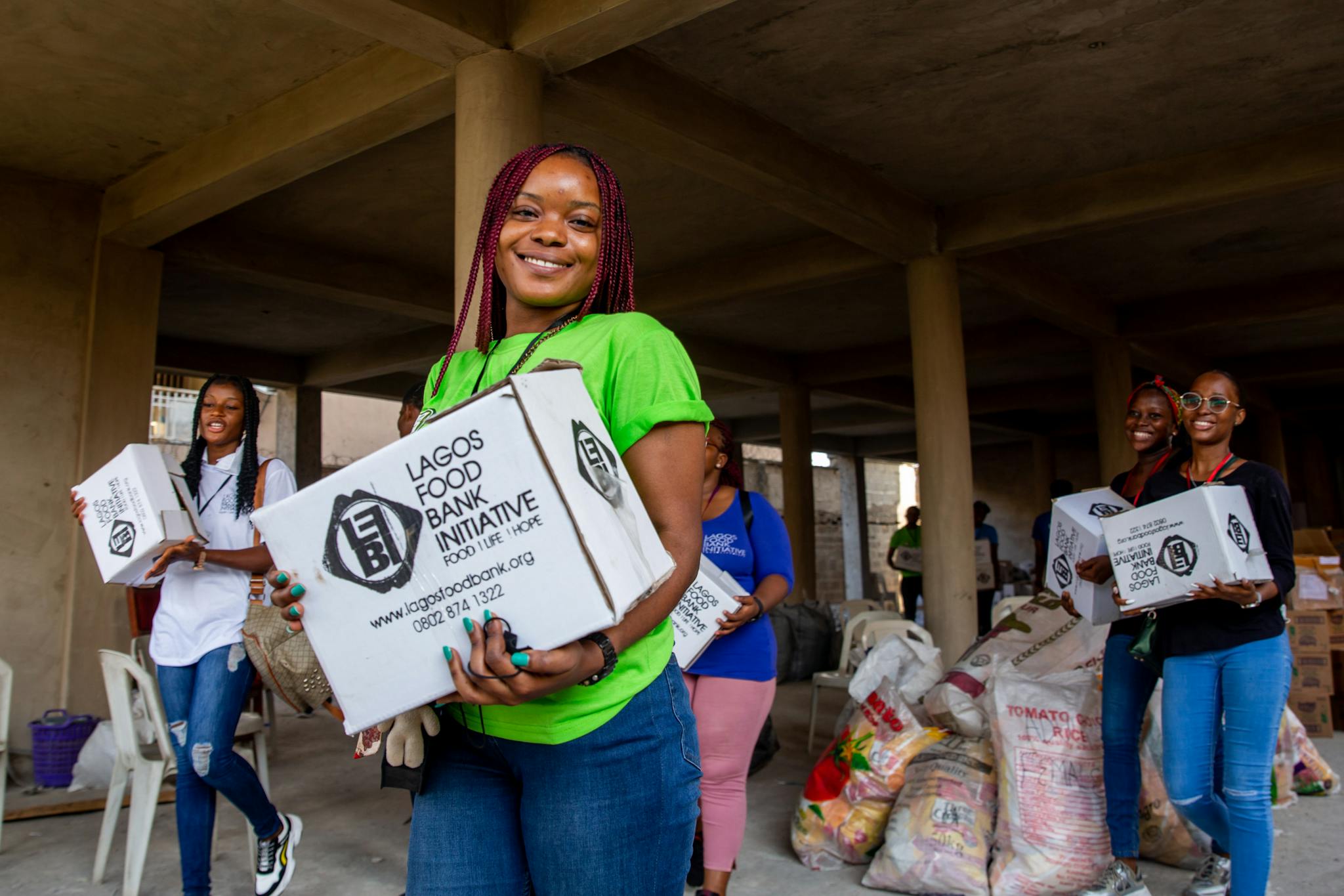 Group of smiling volunteers distributing food boxes at Lagos Food Bank Initiative.