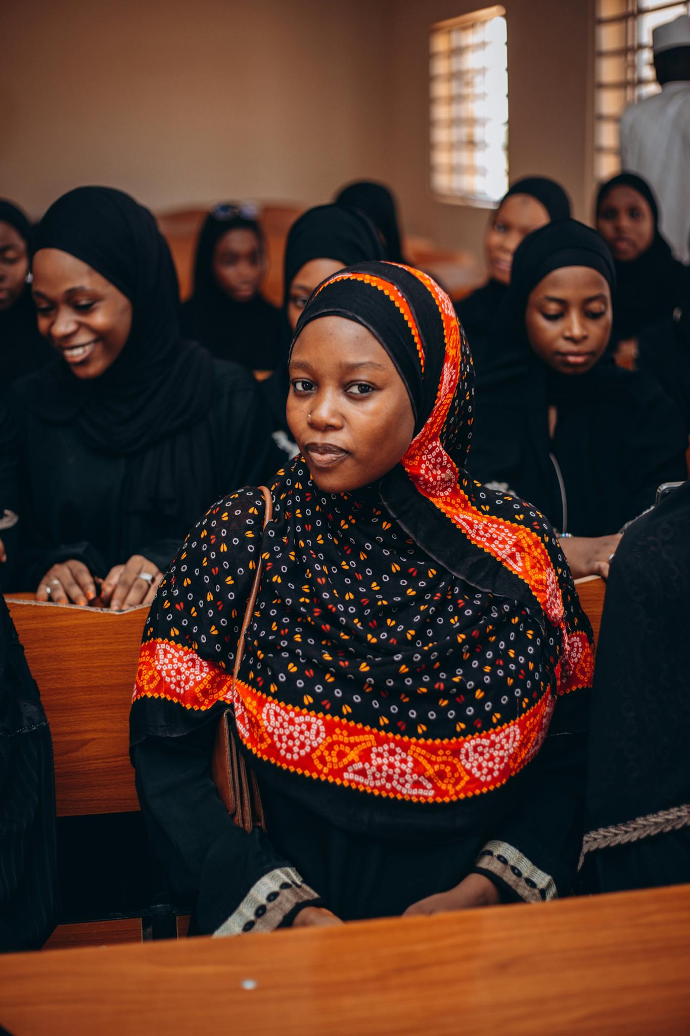 Group of young women wearing colorful hijabs inside a meeting room.